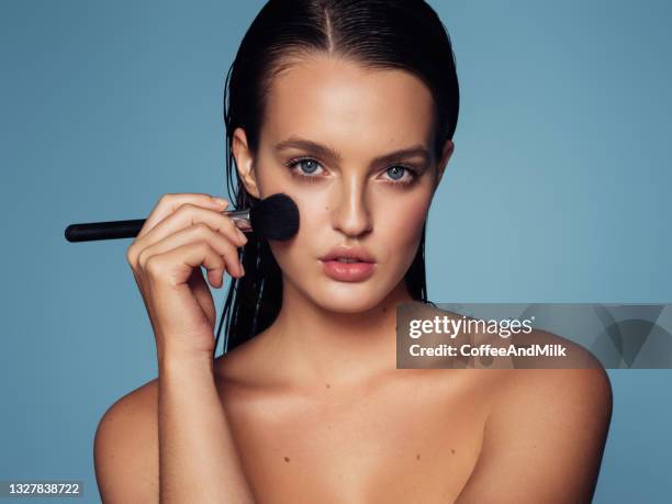 beautiful young woman applying foundation powder - make up blush imagens e fotografias de stock