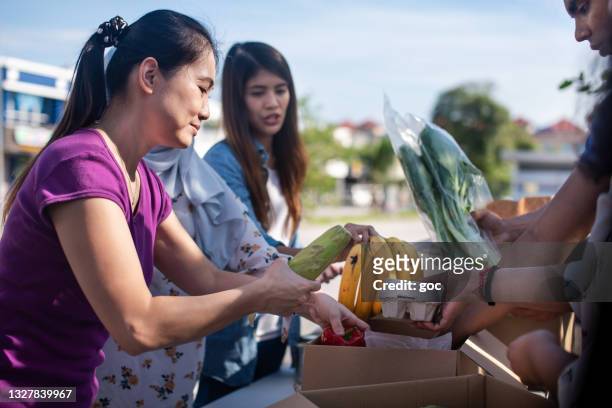 voluntarios de grupos multiétnicos empacando cajas de donación con alimentos en conserva y comestibles durante una campaña de comida al aire libre - food distribution fotografías e imágenes de stock