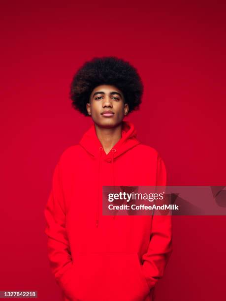 african american man with african hairstyle standing over isolated red background - man and his hoodie imagens e fotografias de stock