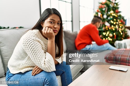 Jovem casal latino em problemas com expressão triste sentado no sofá de casa. Jovem casal latino em problemas com expressão triste sentado no sofá de casa.