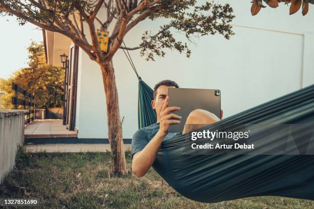 working from summer house with technology during vacations in the backyard with hammock. - hängematte stock-fotos und bilder