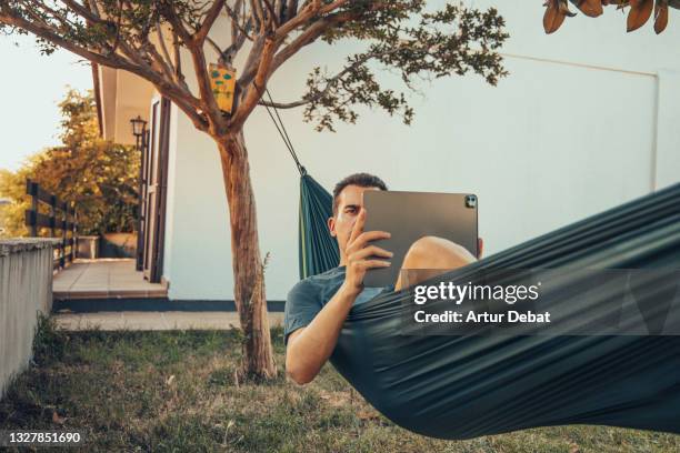 working from summer house with technology during vacations in the backyard with hammock. - hammock imagens e fotografias de stock