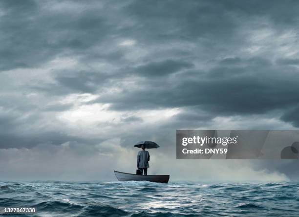 uomo con un ombrello bloccato su una barca - sinking foto e immagini stock