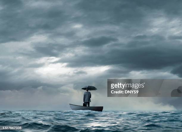 man with an umbrella stranded on a  boat - red boot stockfoto's en -beelden