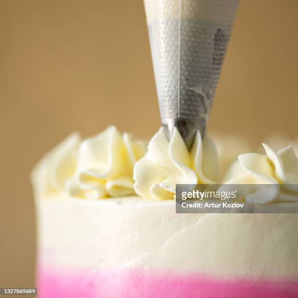 chef decorates cake with cream using pastry syringe. close-up shot. soft focus. copy space - baking competition stock pictures, royalty-free photos & images