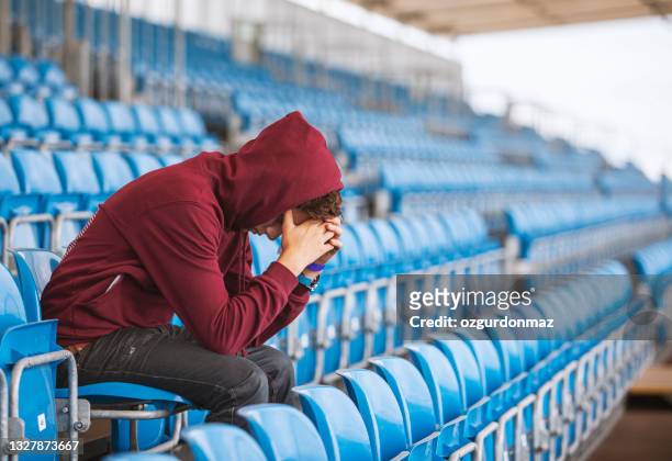 youn disappointed football fan sitting in empty stadium - subdue stock pictures, royalty-free photos & images