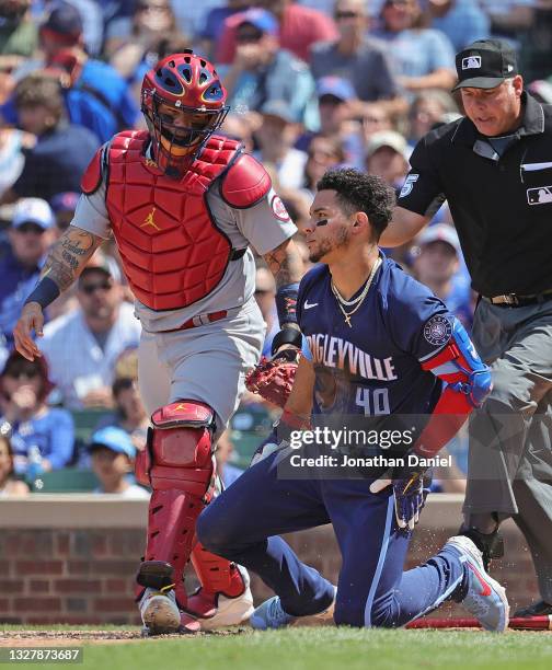 Willson Contreras of the Chicago Cubs looks back at the pitcher after being hit in the head by a pitch as Yadier Molina of the St. Louis Cardinals...