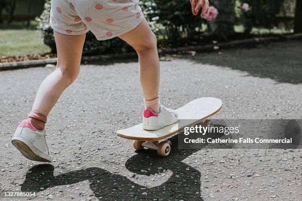 a young girl rides a small skateboard with ease - effortless experience stock pictures, royalty-free photos & images