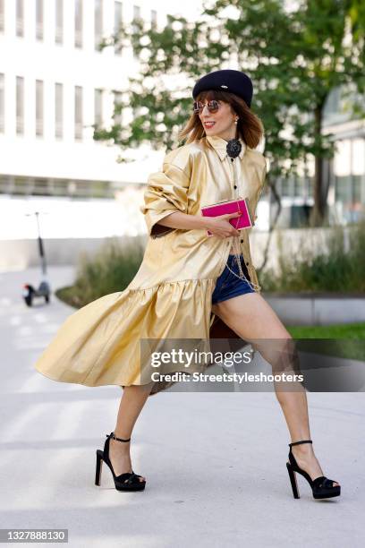 Influencer Salome Chaboki wearing a gold button down midi dress by Rebekka Ruetz, a black flower brooch by Chanel, a dark blue beret hat by...