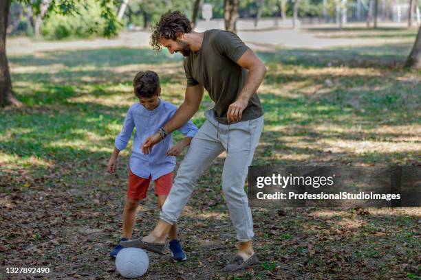 happy family is playing with soccer ball in a park. - kicking ball stock pictures, royalty-free photos & images