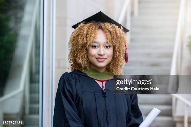 young adult female wearing her cap and gown at graduation - graduation clothing stockfoto's en -beelden