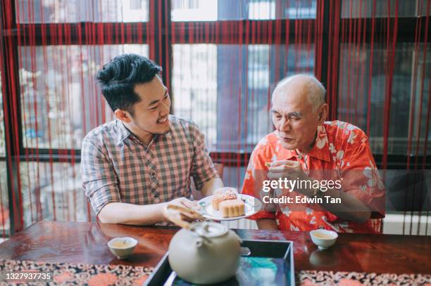 chinese son sharing mooncake to his father during traditional mid-autumn festival at home during afternoon tea gathering - chinese festival stock pictures, royalty-free photos & images
