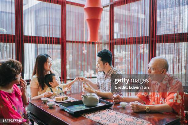 chinese father playing with son during  multi generation enjoying traditional mid-autumn mooncake and chinese tea at home during afternoon tea gathering - mooncake stock pictures, royalty-free photos & images