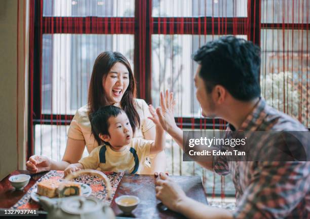 アフタヌーンティーの集まり中に自宅で伝統的な中秋のムーンケーキと中国茶を楽しんでいる間、息子と一緒に中国の父親ハイ5 - 中秋節 ストックフォトと画像