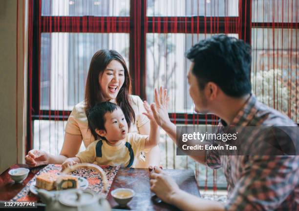 chinese father high five with son during enjoying traditional mid-autumn mooncake and chinese tea at home during afternoon tea gathering - chinese lantern festival stockfoto's en -beelden