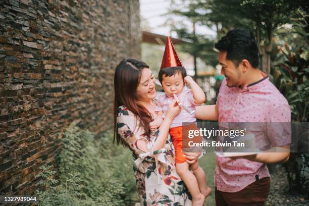 asian chinese young family celebration birthday party at backyard - parents children blow candles asians stock pictures, royalty-free photos & images