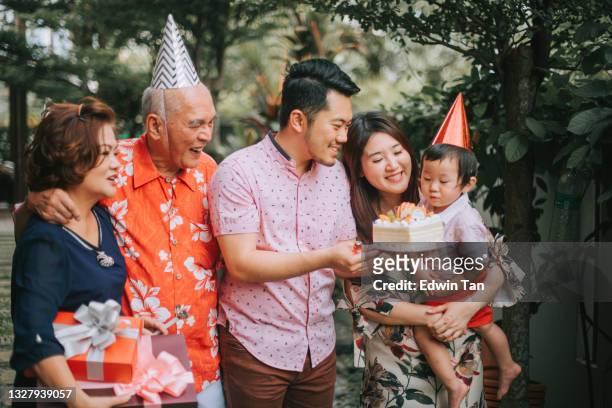 chinese multi generation family celebration birthday party at backyard garden blowing birthday candle for grandfather grandson - chinese birthday stockfoto's en -beelden
