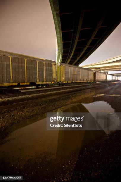 a long line of freight cars pass underneath elevated freeway - oakland california night stock pictures, royalty-free photos & images