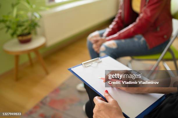 close up of a female psychologist taking notes and a students knees - schoolbegeleider stockfoto's en -beelden