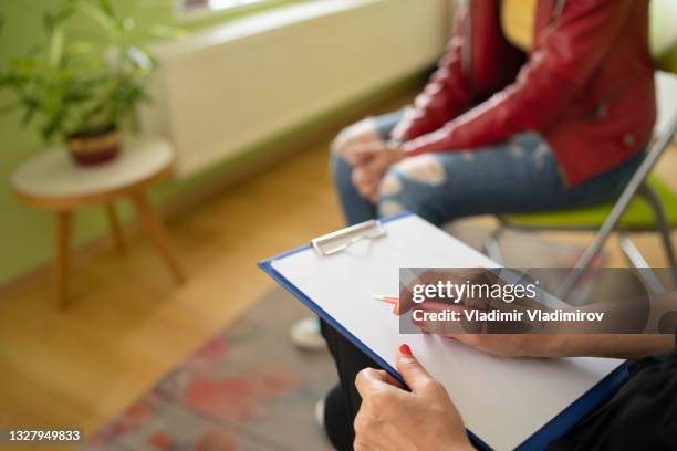 close up of a female psychologist taking notes and a students knees - therapist imagens e fotografias de stock