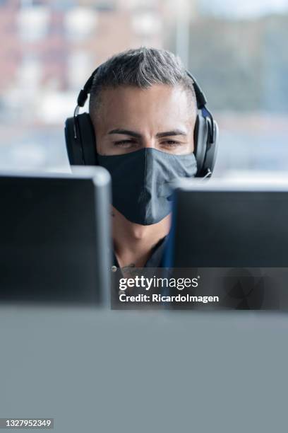 latino male call center worker tends to flames sitting in front of his computer - in flames i the mask stock pictures, royalty-free photos & images