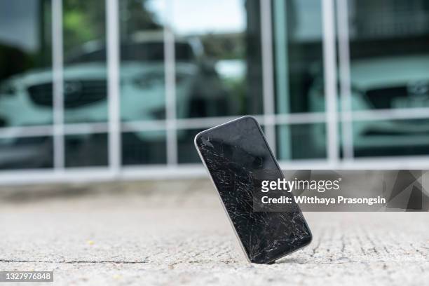 mobile phone falling and crashes on asphalt - broken smartphone fotografías e imágenes de stock
