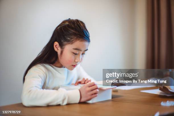 lovely girl using online dictionary on smartphone while reading a book at home - chinese dictionary foto e immagini stock