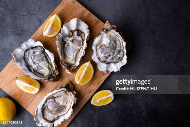 opened oysters on table with lemon - oyster stock pictures, royalty-free photos & images