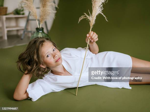 9 years old girl candid portrait with pampas grass branches in a glass bottle on green background, modern interior decoration, cortaderia plant, minimalism background, child portrait - 8 9 years stock pictures, royalty-free photos & images