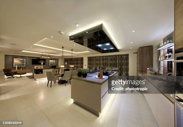 large kitchen and family room in a new luxury home during the evening - downlight stock pictures, royalty-free photos & images
