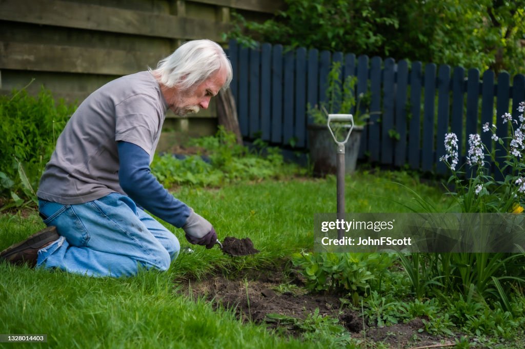Uomo anziano attivo che usa una forchetta per le mani del giardino