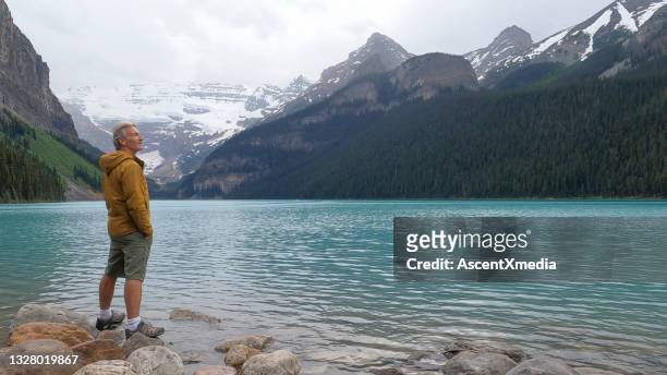 hiker relaxes near beautiful lake louise in the morning - lake louise stock pictures, royalty-free photos & images