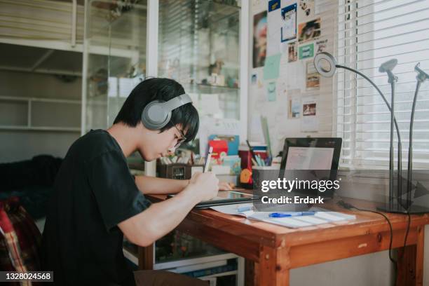 thailändischer nerd männlicher teenager, der mit dem tablet lernt und hausaufgaben macht, um online-fernunterricht zu lernen - stockfoto - male teen tablet stock-fotos und bilder