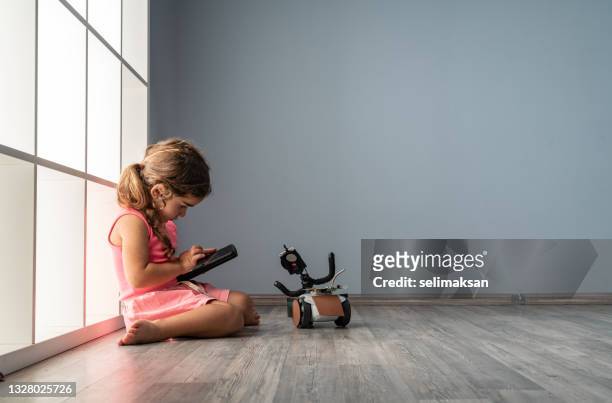 niña jugando con robot en la sala de estar - remote controlled fotografías e imágenes de stock