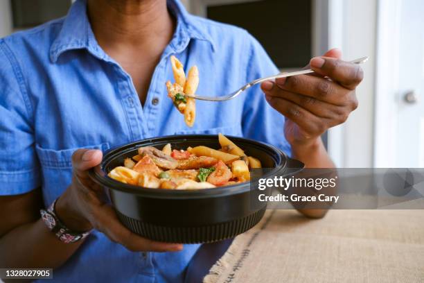 woman eats takeout pasta and chicken dish - woman eating chicken photos et images de collection