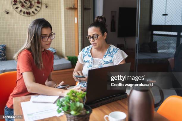 mother and daughter doing finances together at home - family budget imagens e fotografias de stock