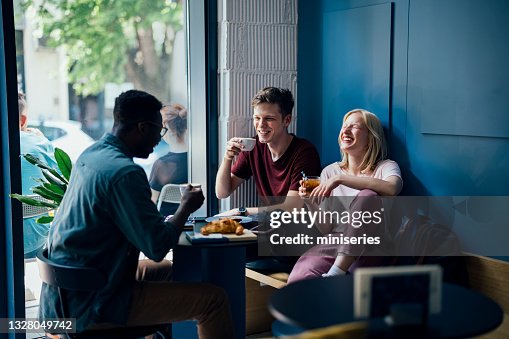 Fröhliche multiethnische Gruppe von Freunden, die zusammen in einem Café frühstücken Fröhliche multiethnische Gruppe von Freunden, die zusammen in einem Café frühstücken