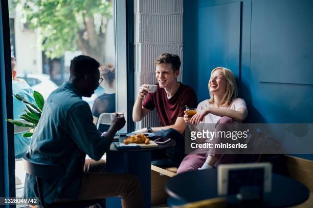 cheerful multi ethnic group of friends having a breakfast togetherâ in a cafe - people eating in bistro stockfoto's en -beelden