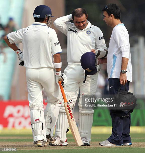 Indian opening batsman Virendra Sehwag gets medical attention as Gautam Gambhir looks on during the first day of second Test match between India and...
