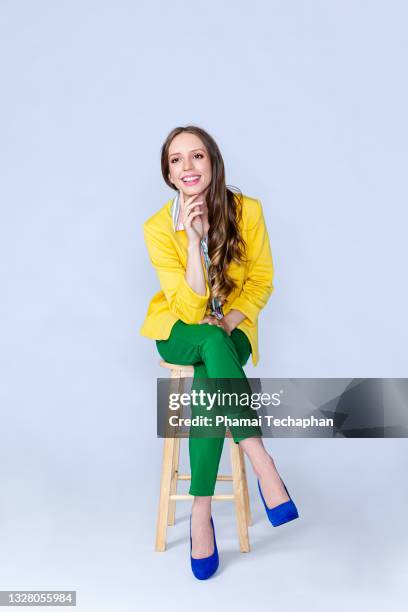 happy woman sitting on a chair - green blazer stockfoto's en -beelden