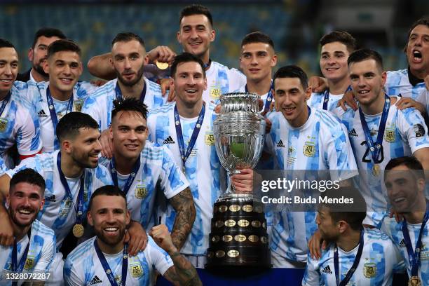 Lionel Messi and Angel Di Maria of Argentina along with teammates pose with the trophy after winning the final of Copa America Brazil 2021 between...