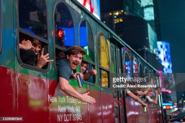 Man screams out the window of a party bus and waves to tourists while driving through Times Square on July 10, 2021 in New York City. New York City...