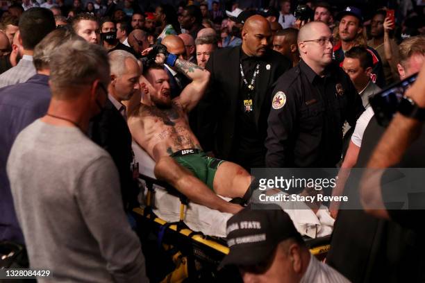 Conor McGregor of Ireland is carried out of the arena on a stretcher after injuring his ankle in the first round of his lightweight bout against...