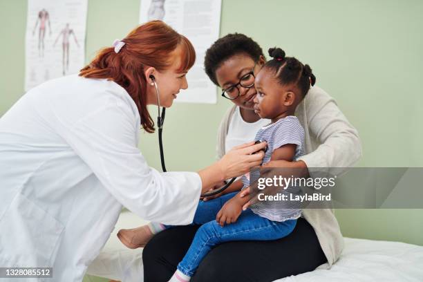 colpo di un medico che esamina un'adorabile bambina con uno stetoscopio durante una consultazione con la madre - pediatrician foto e immagini stock