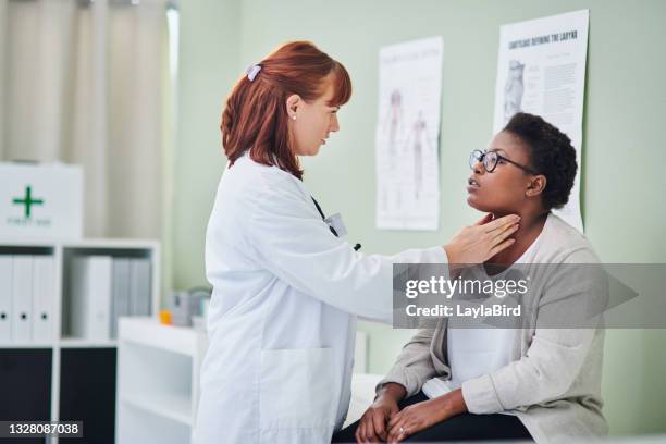 shot of a doctor examining a woman’s throat during a consultation - human gland stockfoto's en -beelden