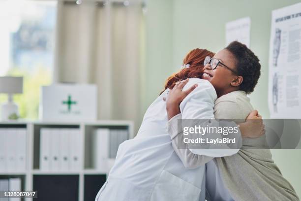 colpo di una giovane donna che abbraccia il suo medico durante una consultazione - abbracciare una persona foto e immagini stock