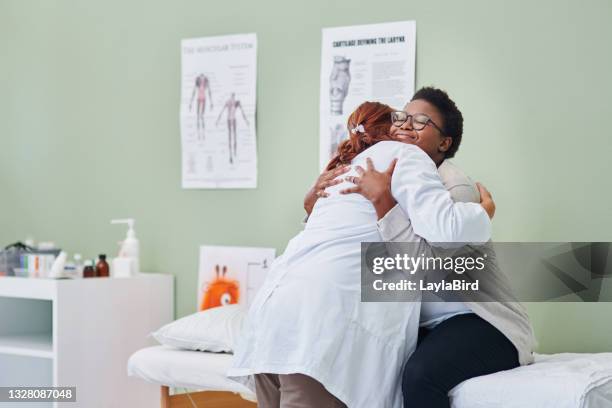 shot of a young woman hugging her doctor during a consultation - doctors embracing stock pictures, royalty-free photos & images