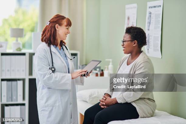 shot of a doctor using a digital tablet during a consultation with a woman - visit stock pictures, royalty-free photos & images