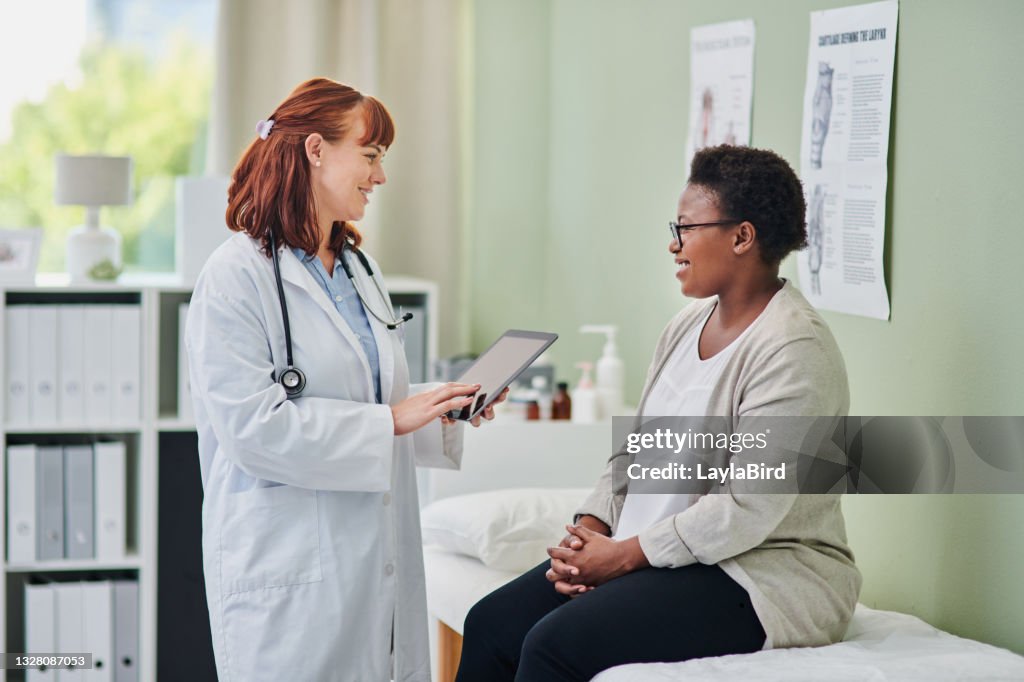 Tiro de um médico usando um tablet digital durante uma consulta com uma mulher