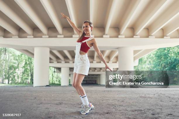 a young beautiful slender woman is dancing the melbourne shuffle dance under the bridge - barajar fotografías e imágenes de stock